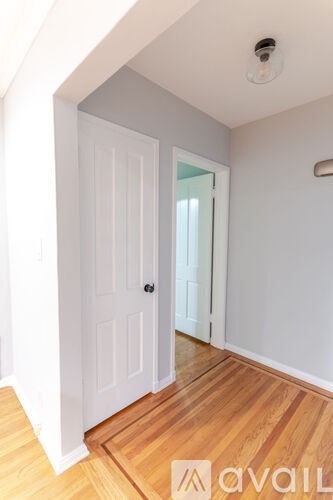 A room with a white door and wooden floor.