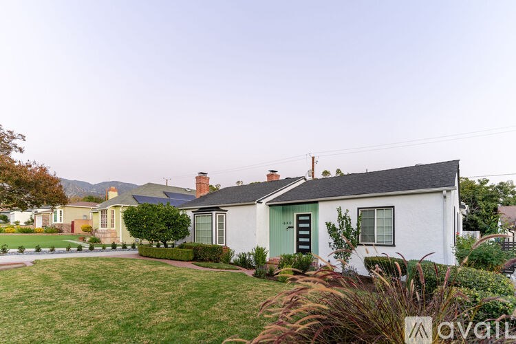 A white house with a green door is surrounded by a well-kept lawn.