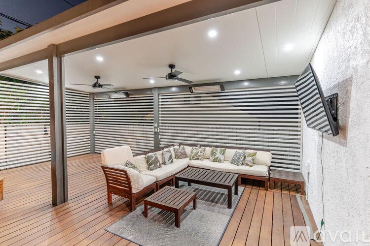 A modern outdoor seating area with a white couch and wooden furniture.