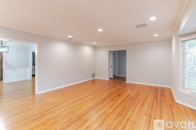 A spacious room with wooden flooring and white walls.