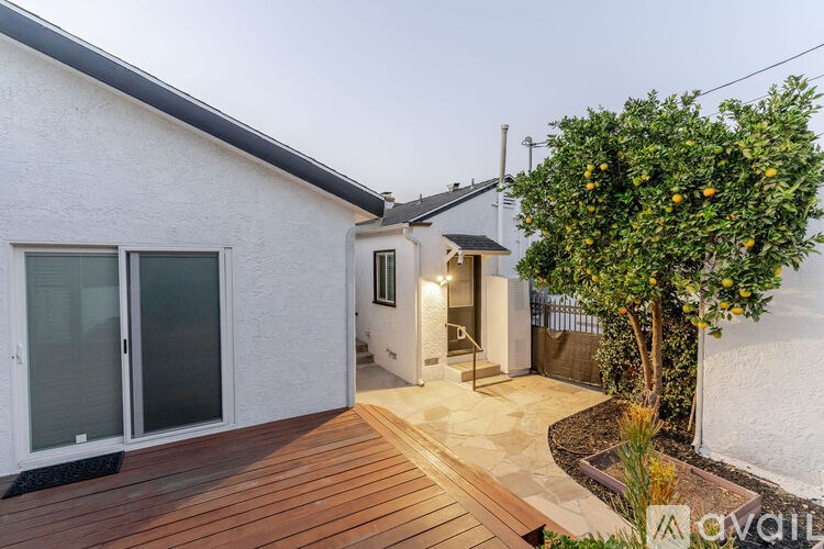 A modern house with a wooden deck and a tree with oranges growing on it.