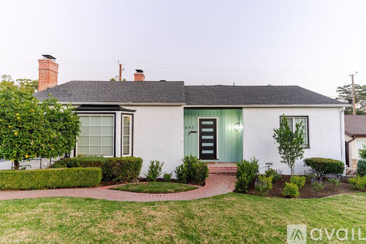 A white house with a green door and a brick pathway leading to it.