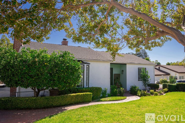 A white house with a tree in front of it.