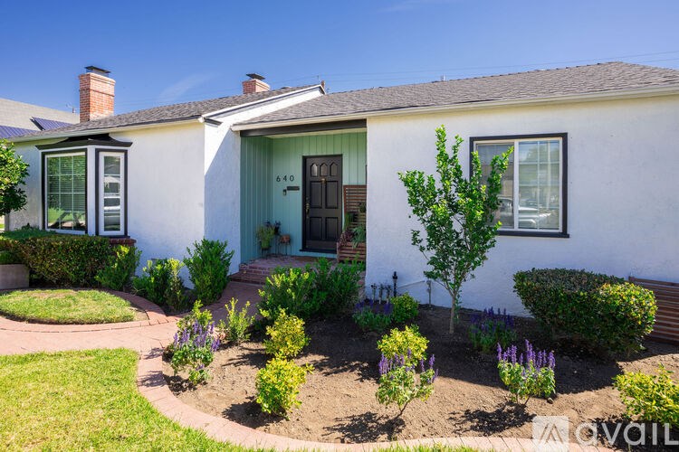 A white house with a green door and a small garden in front.