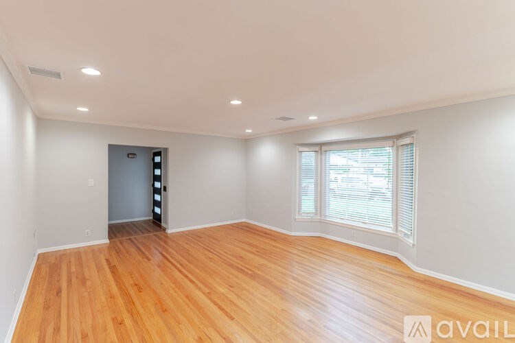 A room with wooden floors and a door leading to another room.
