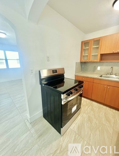 A kitchen with a black stove top oven and wooden cabinets.
