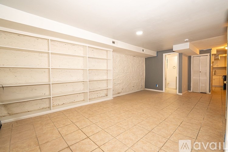 A large empty room with a tiled floor and a wall of shelves.