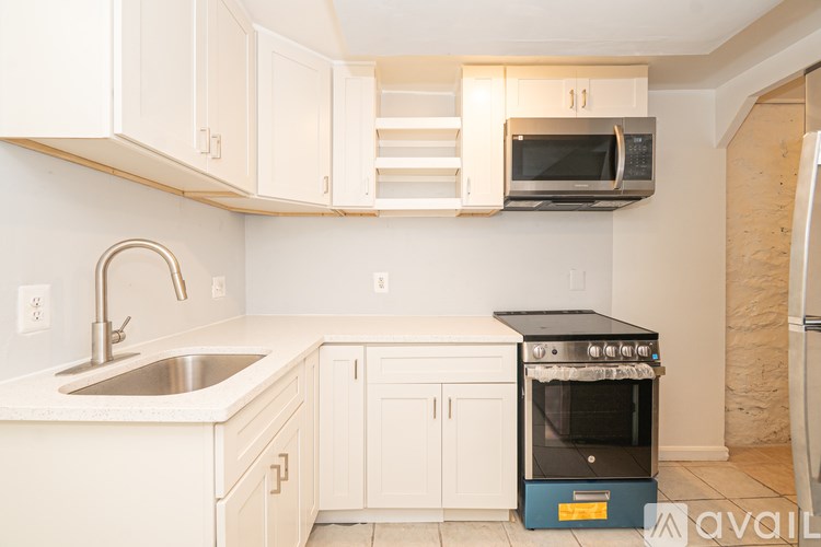 A kitchen with a sink, stove, and cabinets.