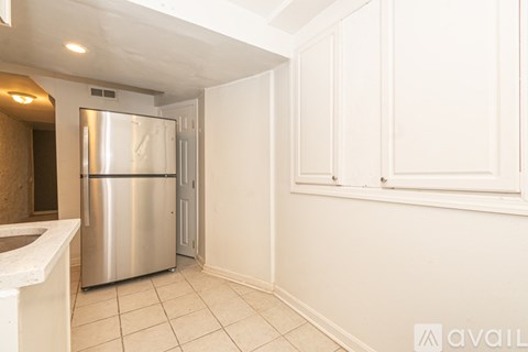 A kitchen with a stainless steel refrigerator and white cabinets.