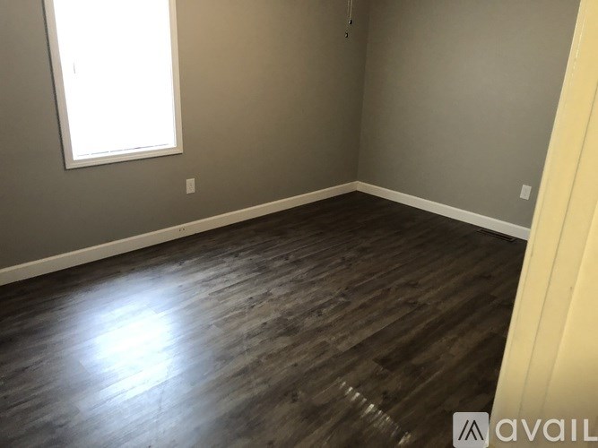 A room with wooden flooring and a window letting in light.