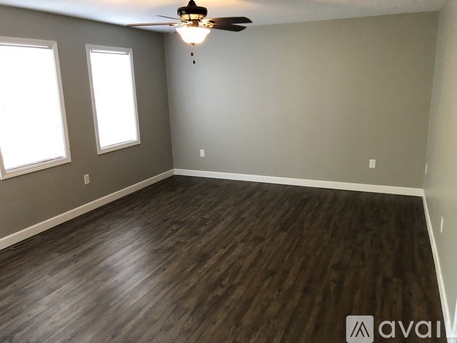 A room with wooden flooring and a ceiling fan.