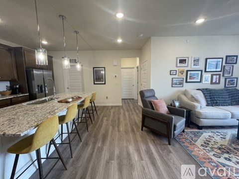 A modern kitchen with a marble countertop and yellow chairs.