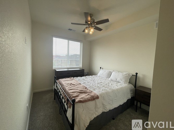 A bedroom with a bed, a ceiling fan, and a window with blinds.