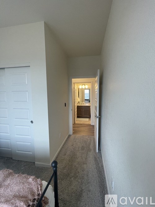 A hallway with a white door and a light at the end.