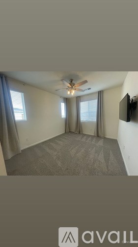 A room with a ceiling fan and a flat screen TV mounted on the wall.