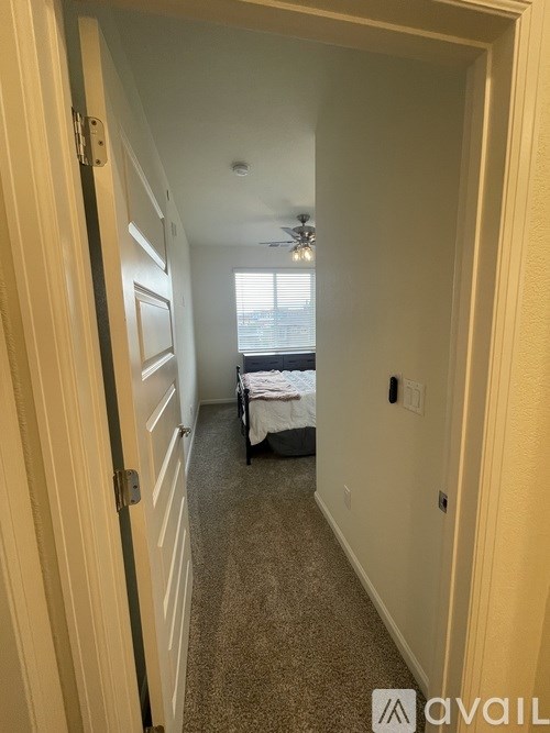 A hallway with a bed in the distance and a carpeted floor.