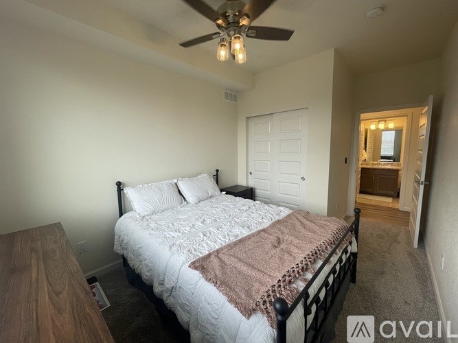 A bedroom with a bed, dresser, and a ceiling fan.