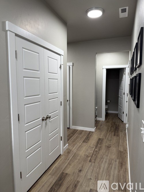 A hallway with white doors and wood flooring.