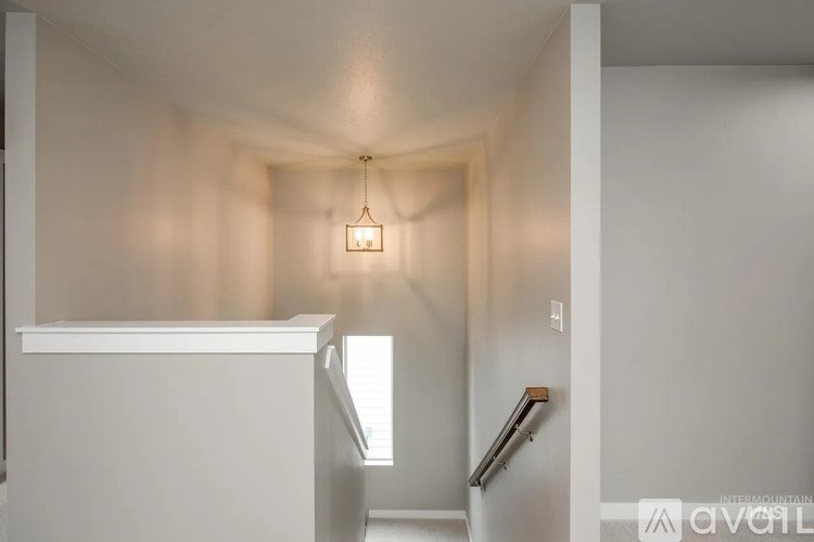 A hallway with a light hanging from the ceiling and a staircase on the right.
