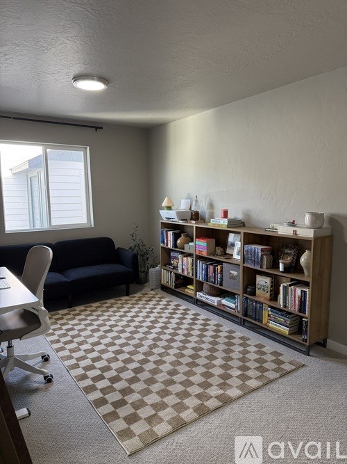 A room with a checkered rug, a blue couch, and a bookshelf.