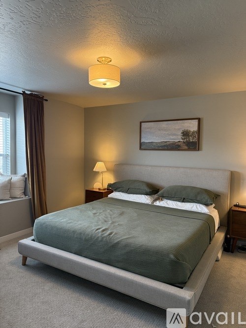 A bedroom with a bed, nightstands, and a painting on the wall.