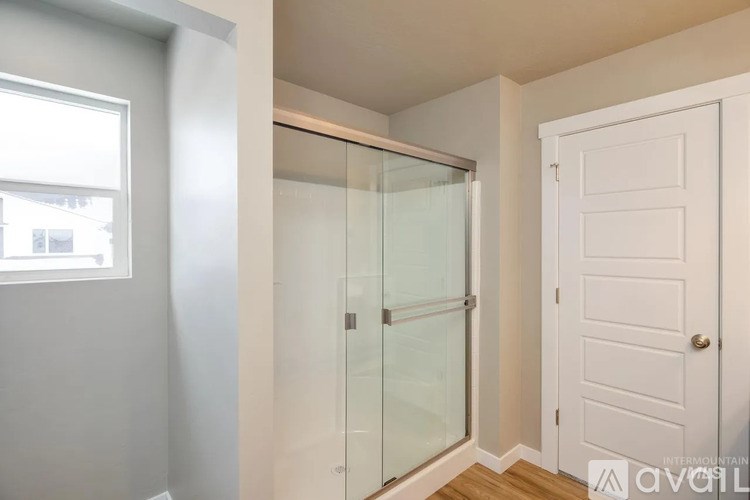 A white door is on the right side of a glass shower stall.