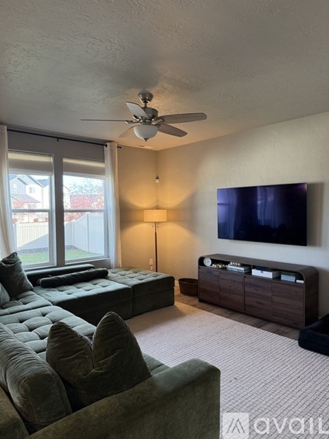 A living room with a grey couch and a flat screen TV mounted on the wall.