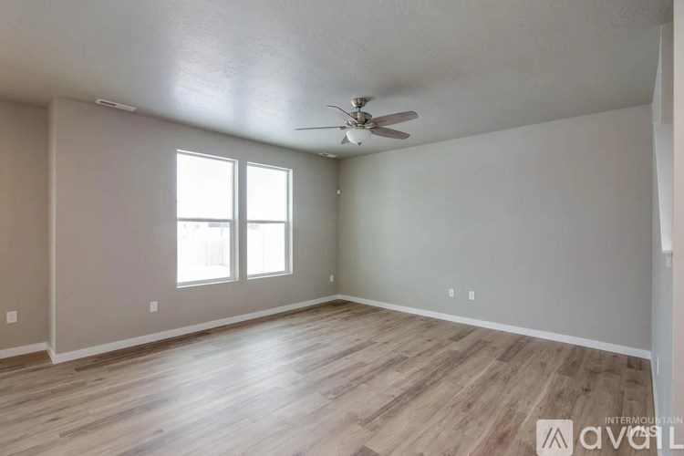 A spacious room with wooden flooring and a ceiling fan.