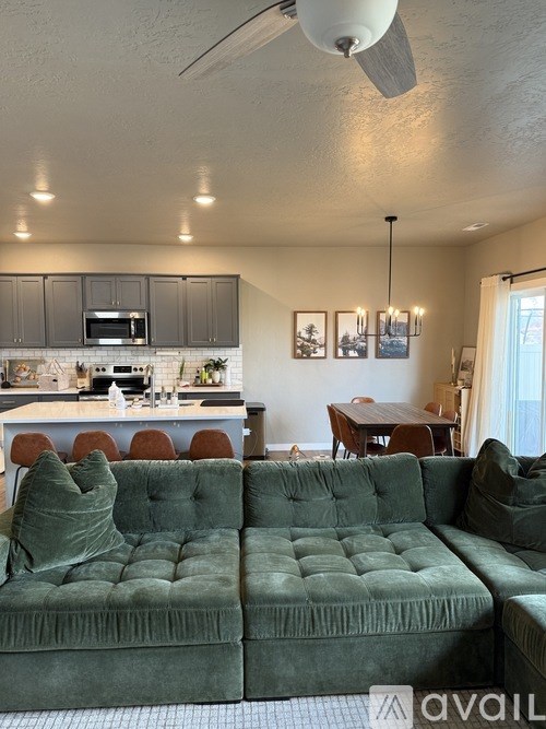 A living room with a green couch and a kitchen area in the background.