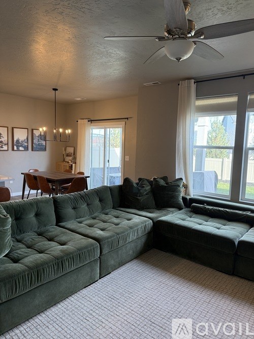 A living room with a green couch and a ceiling fan.