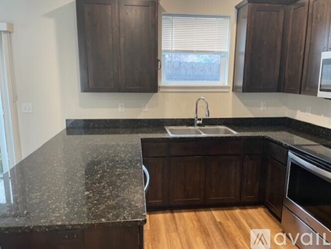 A kitchen with dark wood cabinets and granite countertops.