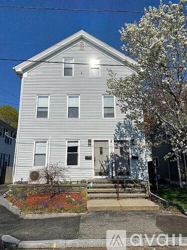 A two-story house with a front yard and a tree in bloom.