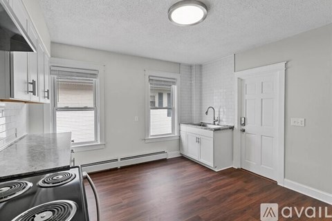 A kitchen with a stove top oven and wooden floors.