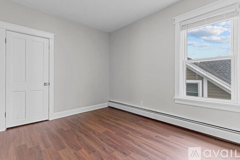 A room with a wooden floor and a window showing a house and sky.