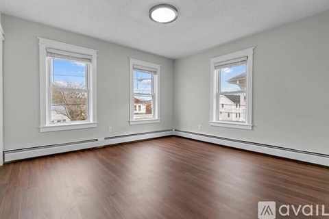 A room with wooden floors and three windows.