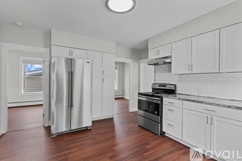A kitchen with white cabinets and a stainless steel refrigerator.