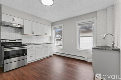 A kitchen with white cabinets and a wooden floor.