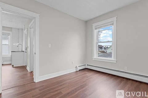 A room with a window and wooden floors is available for rent.