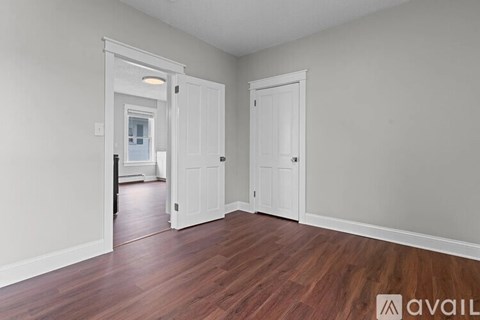 A room with wooden floors and white walls with two doors.