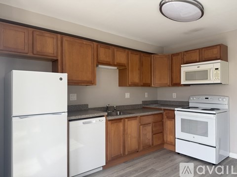 A kitchen with white appliances and wooden cabinets.