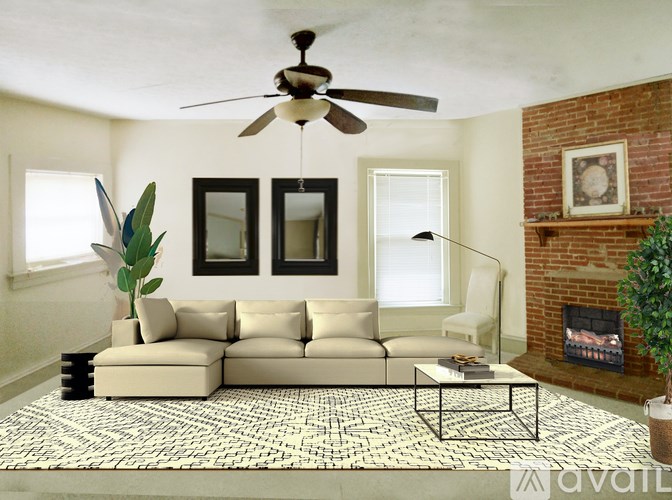 A living room with a beige sofa, a fan, and a fireplace.
