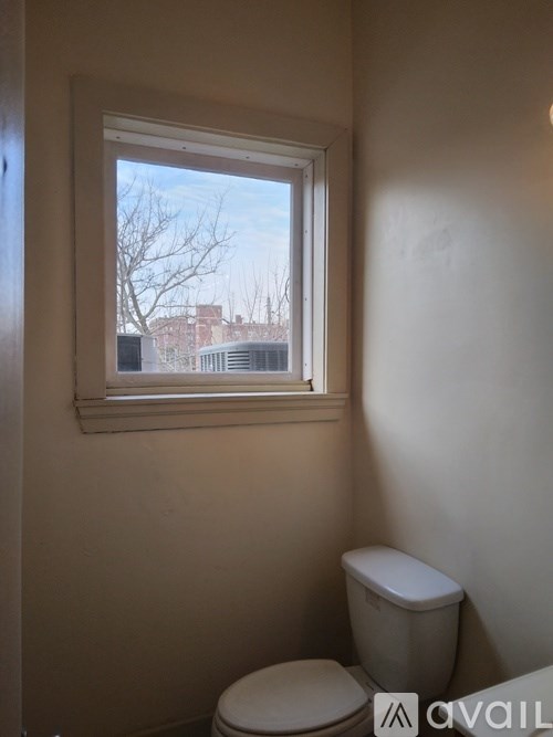 A white toilet sits in a bathroom next to a window.