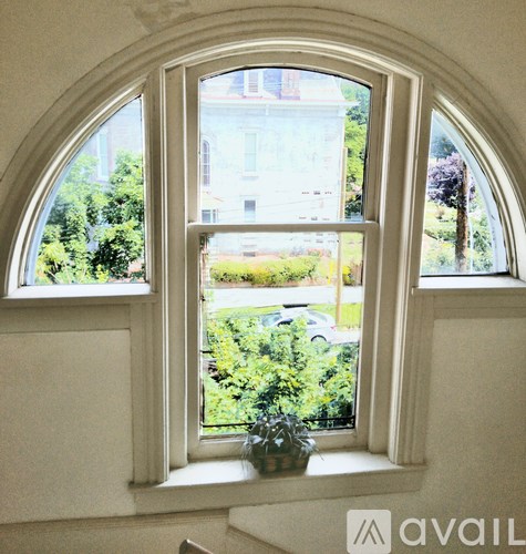 A window with a view of a building and greenery outside.