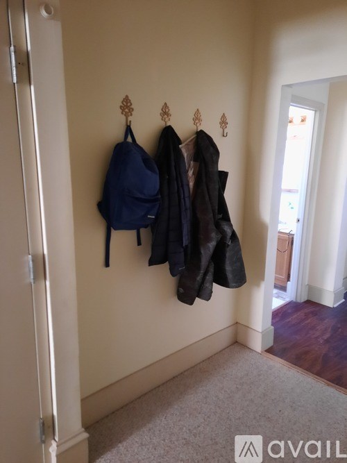 A hallway with a coat rack and a backpack hanging on it.