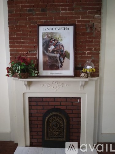 A framed picture of a woman named Lynne Yancha is on a mantle above a fireplace.