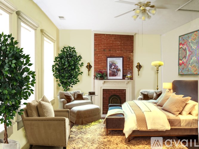 A bedroom with a fireplace, a bed, a chair, and a tree.