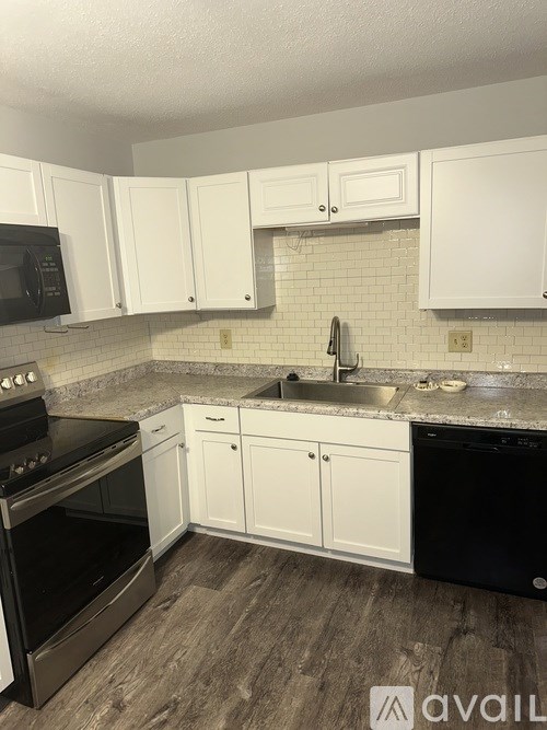 A kitchen with black appliances and white cabinets.