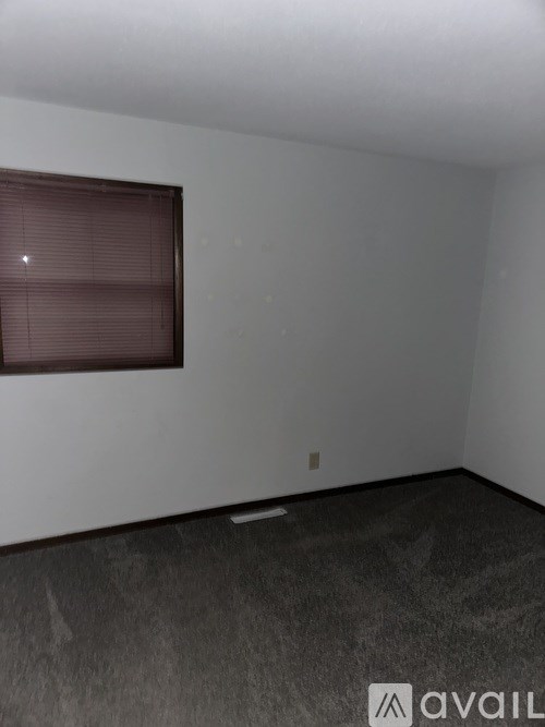 A room with a window and a carpeted floor.