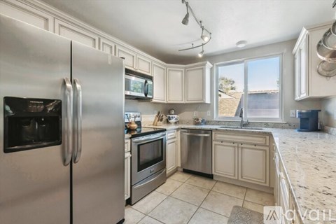 A kitchen with a stainless steel refrigerator and a marble countertop.