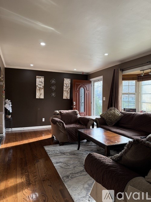 A living room with brown furniture and a wooden floor.